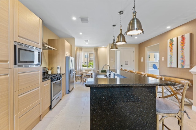 3149 Brasilia Ave, Kissimmee, FL 34747 - kitchen featuring stainless steel appliances, a spacious island, a kitchen breakfast bar, light tile patterned floors, and light brown cabinetry