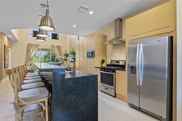 3149 Brasilia Ave, Kissimmee, FL 34747 - kitchen with appliances with stainless steel finishes, wall chimney exhaust hood, light tile patterned floors, light brown cabinets, and a kitchen bar
