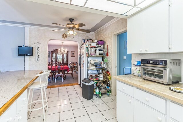 251 Tropic Blvd W, Largo, FL 33770 - kitchen with arched walkways, light tile patterned floors, a chandelier, ornamental molding, and white cabinets
