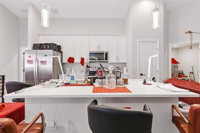 999 Trumbull St, Deltona, FL 32725 - kitchen featuring stainless steel appliances, a kitchen bar, white cabinetry, decorative light fixtures, and light countertops