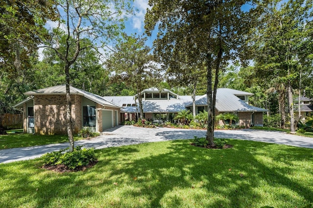 20 Twelve Oaks Trl, Ormond Beach, FL 32174 - mid-century inspired home featuring driveway, an attached garage, a front yard, metal roof, and brick siding