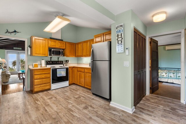 4039 S Atlantic Ave, Port Orange, FL 32127 - kitchen featuring appliances with stainless steel finishes, a wall mounted air conditioner, light countertops, light wood-style flooring, and high vaulted ceiling