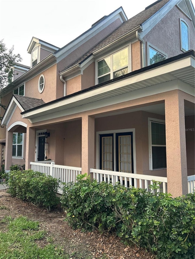 3417 Westchester Square Blvd Unit 202, Orlando, FL 32835 - view of property exterior featuring covered porch, stucco siding, and a shingled roof