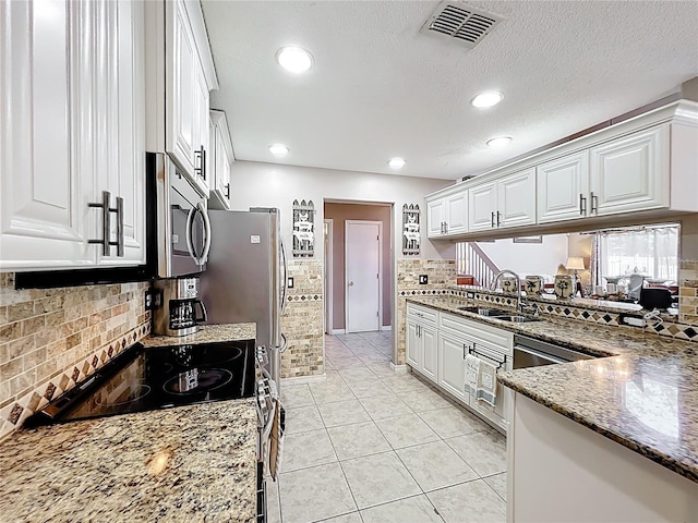 1803 Meadow Pond Way, Orlando, FL 32824 - kitchen featuring stainless steel microwave, a sink, range with electric cooktop, white cabinets, and stone countertops