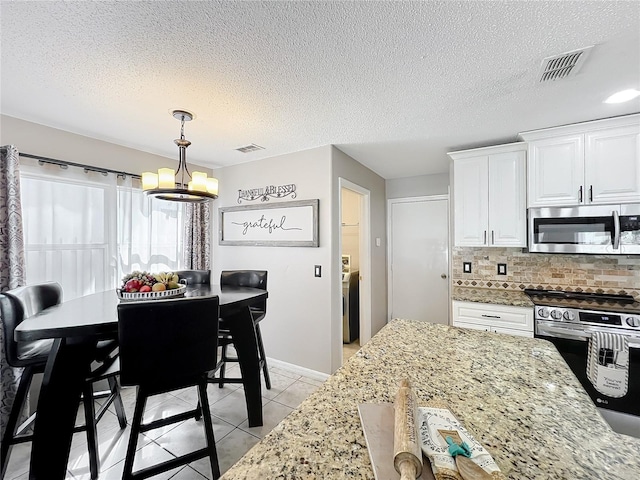 1803 Meadow Pond Way, Orlando, FL 32824 - kitchen featuring appliances with stainless steel finishes, a chandelier, light stone counters, white cabinetry, and decorative backsplash