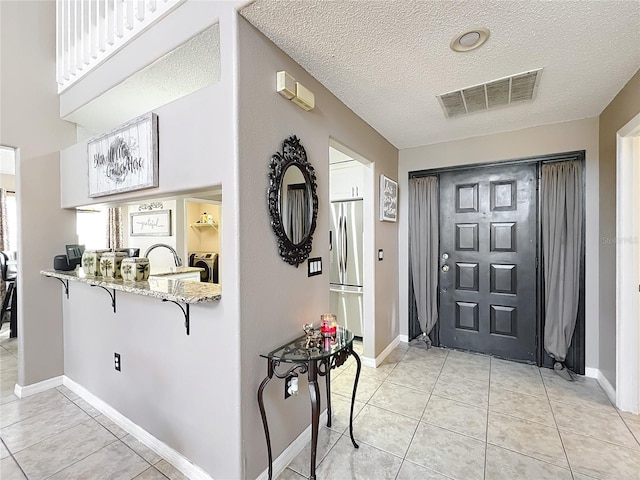 1803 Meadow Pond Way, Orlando, FL 32824 - foyer with light tile patterned floors, a textured ceiling, and baseboards