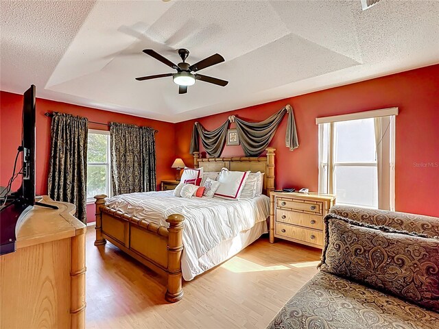 1803 Meadow Pond Way, Orlando, FL 32824 - bedroom with light wood-style floors, a tray ceiling, a ceiling fan, and a textured ceiling