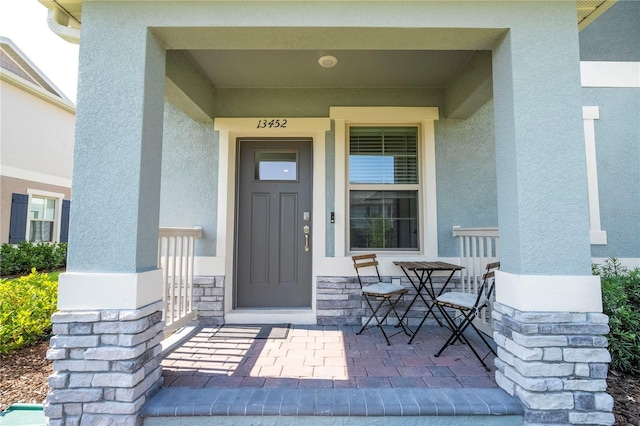 13452 Sagestone Dr, Winter Garden, FL 34787 - doorway to property featuring stucco siding, covered porch, and stone siding