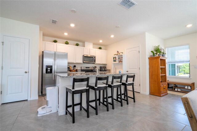 13452 Sagestone Dr, Winter Garden, FL 34787 - kitchen with stainless steel appliances, light stone countertops, an island with sink, recessed lighting, and white cabinetry