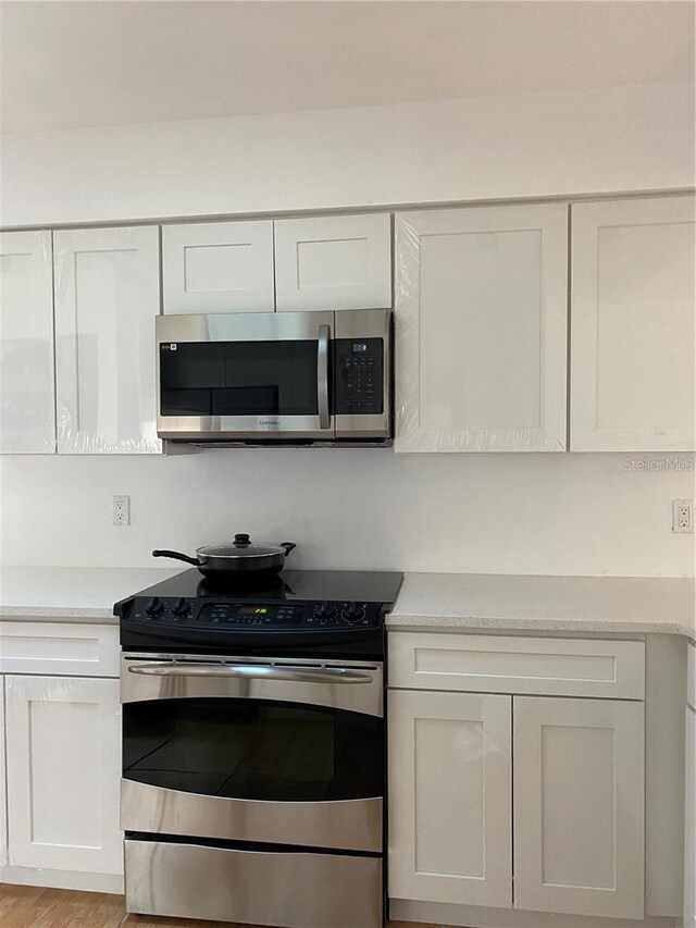 1422 Spalding Rd, Winter Springs, FL 32708 - kitchen featuring appliances with stainless steel finishes, light countertops, white cabinetry, and light wood finished floors