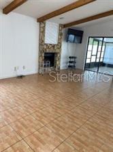 1422 Spalding Rd, Winter Springs, FL 32708 - unfurnished living room featuring beamed ceiling, tile patterned flooring, and a fireplace