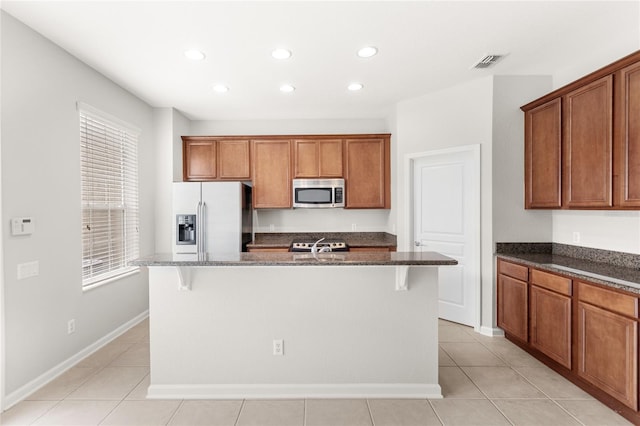 7715 Anselmo Ln, Windermere, FL 34786 - kitchen with stainless steel appliances, recessed lighting, dark stone counters, brown cabinets, and a center island with sink