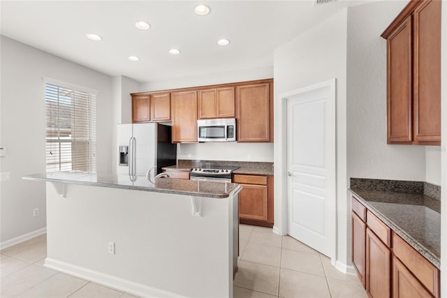 7715 Anselmo Ln, Windermere, FL 34786 - kitchen featuring stainless steel appliances, recessed lighting, dark stone countertops, brown cabinetry, and a center island with sink
