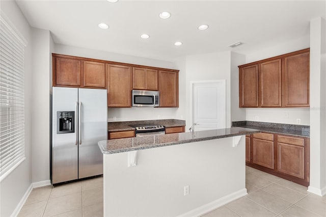 7715 Anselmo Ln, Windermere, FL 34786 - kitchen with stainless steel appliances, dark stone countertops, light tile patterned flooring, brown cabinets, and recessed lighting