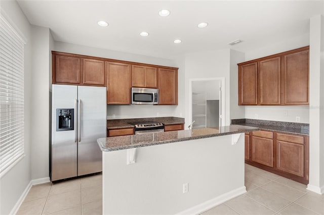 7715 Anselmo Ln, Windermere, FL 34786 - kitchen with appliances with stainless steel finishes, light tile patterned floors, dark stone counters, brown cabinetry, and recessed lighting