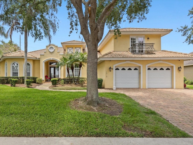 1319 Johns Cove Ln, Oakland, FL 34787 - mediterranean / spanish house featuring french doors, a balcony, decorative driveway, a front lawn, and stucco siding