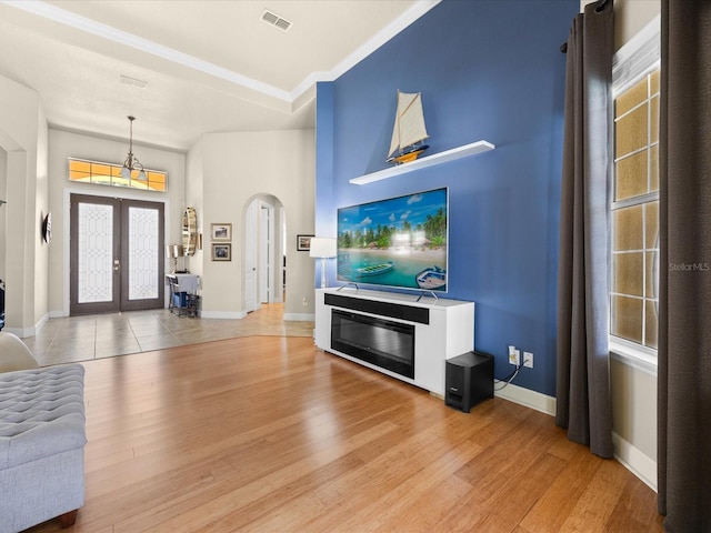 1319 Johns Cove Ln, Oakland, FL 34787 - living area with arched walkways, light wood-type flooring, french doors, ornamental molding, and baseboards
