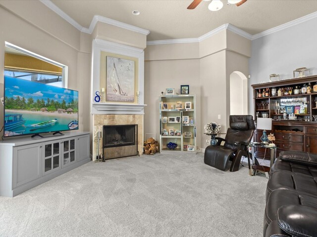 1319 Johns Cove Ln, Oakland, FL 34787 - living area featuring a tile fireplace, a ceiling fan, crown molding, arched walkways, and carpet flooring
