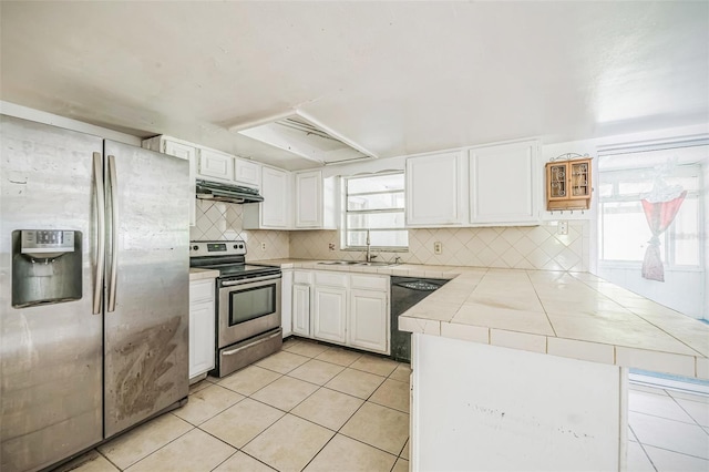 1601 Randolph St, Deltona, FL 32725 - kitchen featuring stainless steel appliances, under cabinet range hood, a peninsula, tile countertops, and a sink