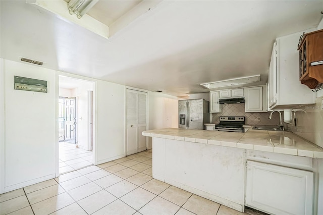 1601 Randolph St, Deltona, FL 32725 - kitchen featuring appliances with stainless steel finishes, under cabinet range hood, a sink, light tile patterned floors, and tile countertops