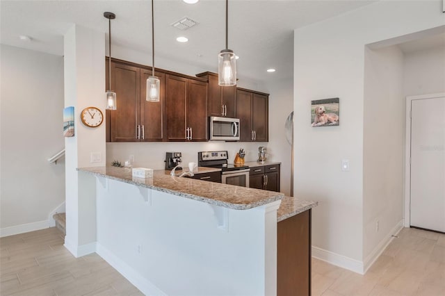 15241 Sunrise Grove Ct, Winter Garden, FL 34787 - kitchen featuring stainless steel appliances, a breakfast bar, light stone counters, a peninsula, and decorative light fixtures