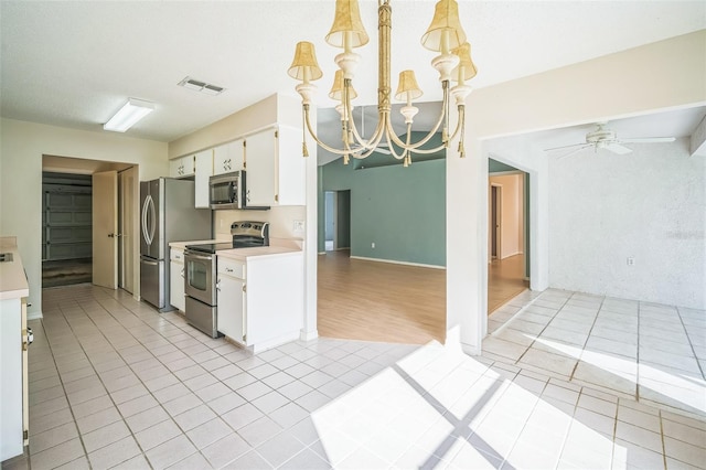 2015 Gardenia Landings Ln, Sun City Center, FL 33573 - kitchen featuring appliances with stainless steel finishes, light countertops, white cabinets, light tile patterned flooring, and a chandelier