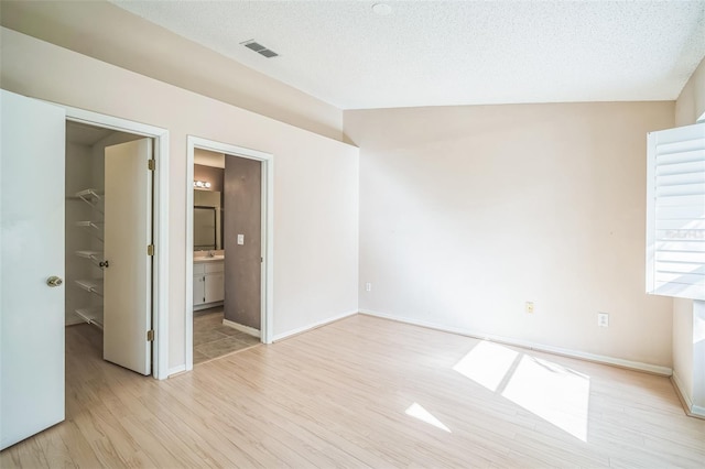 2015 Gardenia Landings Ln, Sun City Center, FL 33573 - unfurnished bedroom with a spacious closet, light wood finished floors, a sink, lofted ceiling, and a closet
