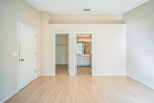 2015 Gardenia Landings Ln, Sun City Center, FL 33573 - unfurnished bedroom with light wood-type flooring, a spacious closet, a closet, and baseboards