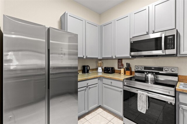 110 Watling Way Unit 25204, Davenport, FL 33837 - kitchen featuring stainless steel appliances, light countertops, light tile patterned flooring, and gray cabinetry