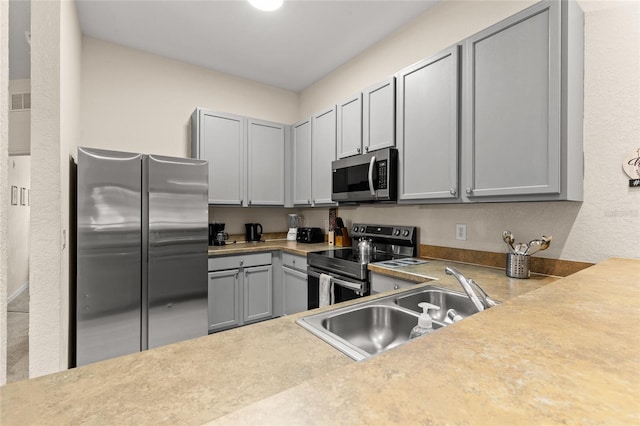 110 Watling Way Unit 25204, Davenport, FL 33837 - kitchen featuring stainless steel appliances, a sink, gray cabinets, light countertops, and a textured wall