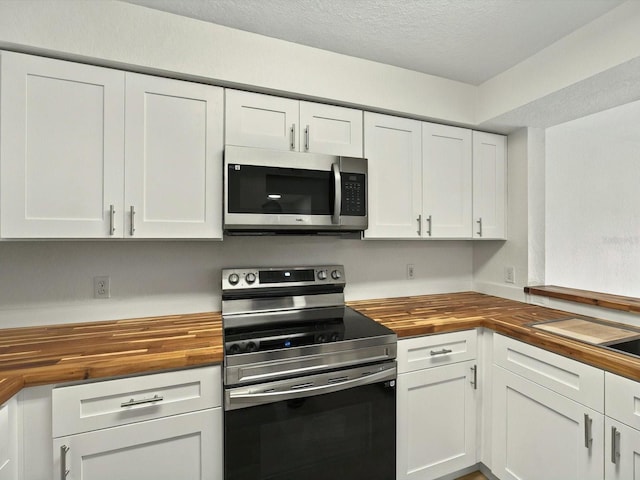 13917 Fairway Island Dr Unit 931, Orlando, FL 32837 - kitchen with wooden counters, appliances with stainless steel finishes, white cabinetry, and a textured ceiling
