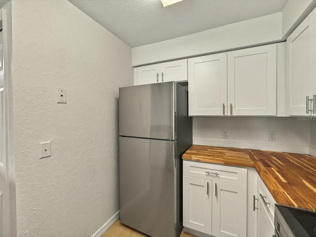 13917 Fairway Island Dr Unit 931, Orlando, FL 32837 - kitchen featuring wooden counters, freestanding refrigerator, a textured wall, white cabinetry, and stove