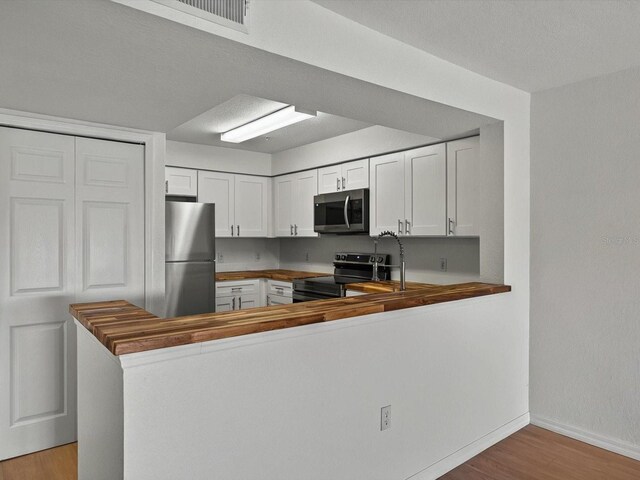13917 Fairway Island Dr Unit 931, Orlando, FL 32837 - kitchen with stainless steel appliances, wood counters, light wood-type flooring, baseboards, and white cabinetry