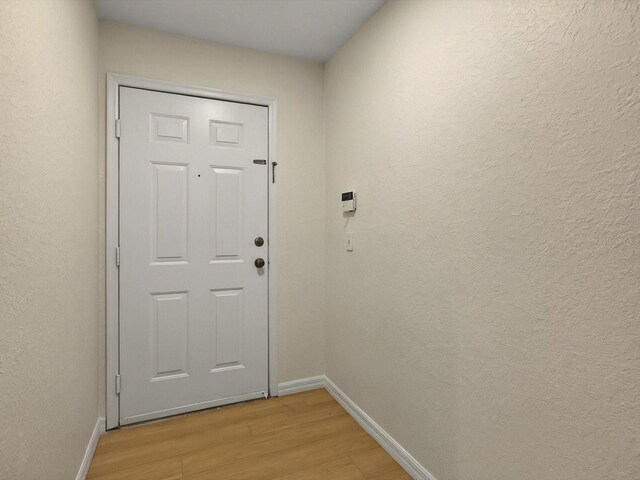 13917 Fairway Island Dr Unit 931, Orlando, FL 32837 - doorway to outside featuring light wood-style floors, baseboards, and a textured wall
