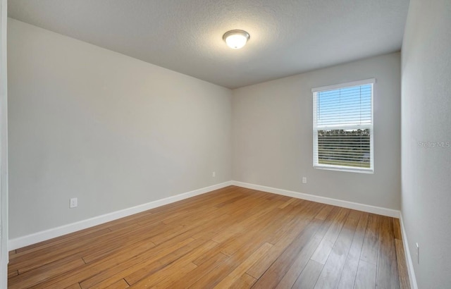 491 Whistling Duck Trl, Saint Cloud, FL 34771 - empty room featuring baseboards, light wood-style flooring, and a textured ceiling