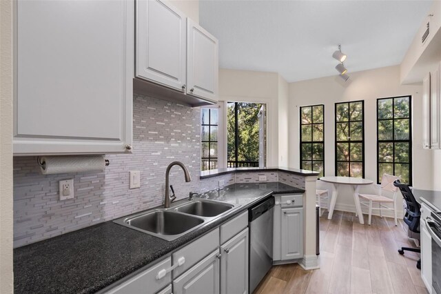 500 Mirasol Cir Unit 203, Celebration, FL 34747 - kitchen featuring stainless steel dishwasher, a sink, decorative backsplash, dark countertops, and a peninsula