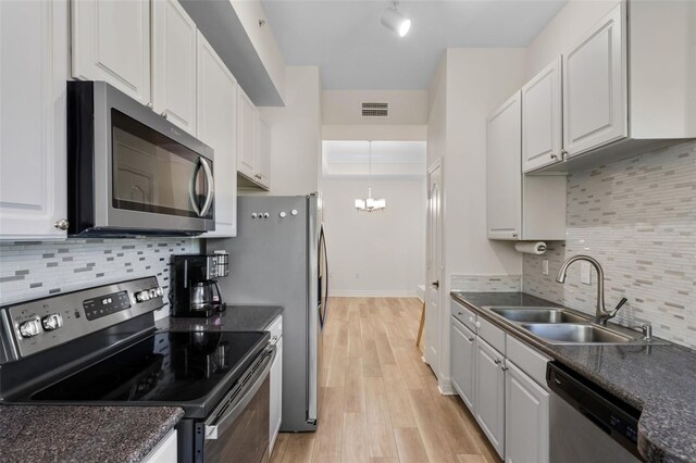 500 Mirasol Cir Unit 203, Celebration, FL 34747 - kitchen featuring appliances with stainless steel finishes, a sink, a chandelier, light wood finished floors, and tasteful backsplash