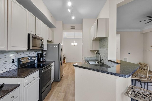 500 Mirasol Cir Unit 203, Celebration, FL 34747 - kitchen with stainless steel appliances, white cabinetry, tasteful backsplash, light wood-style flooring, and dark stone countertops