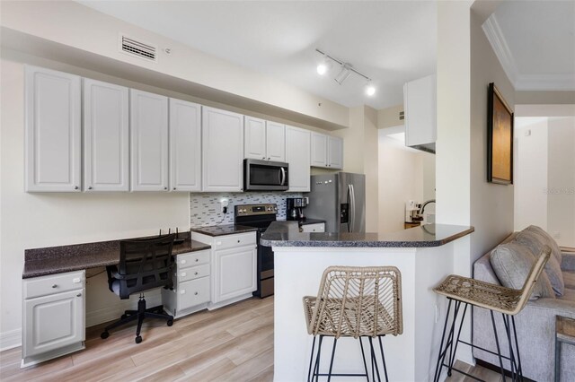 500 Mirasol Cir Unit 203, Celebration, FL 34747 - kitchen featuring stainless steel appliances, dark countertops, a breakfast bar area, white cabinetry, and ornamental molding