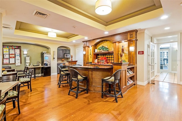 500 Mirasol Cir Unit 203, Celebration, FL 34747 - community bar area with a tray ceiling, crown molding, light wood-style flooring, stainless steel microwave, and baseboards