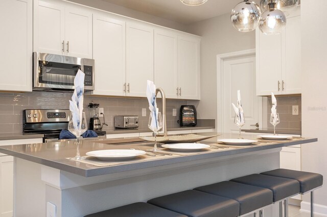 8964 Takeaway Way, Davenport, FL 33896 - kitchen with stainless steel appliances, a kitchen breakfast bar, tasteful backsplash, and white cabinetry
