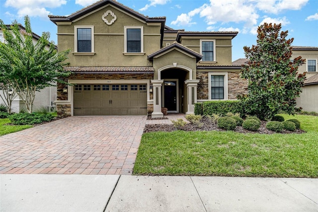 1403 Rolling Fairway Dr, Davenport, FL 33896 - view of front of home with stone siding, decorative driveway, stucco siding, and an attached garage