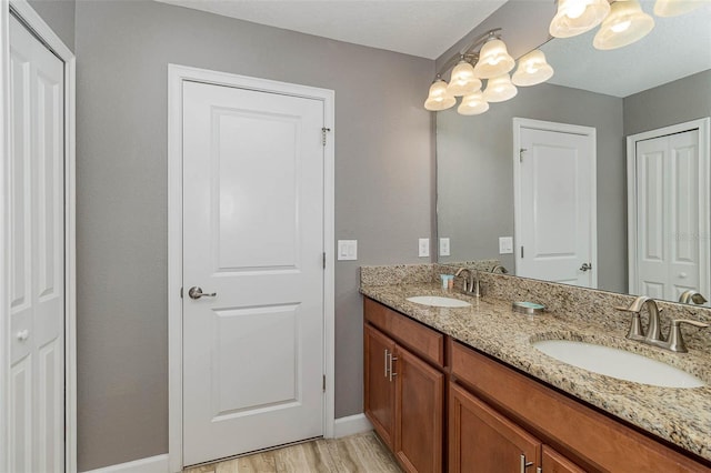 1403 Rolling Fairway Dr, Davenport, FL 33896 - bathroom featuring double vanity, baseboards, a chandelier, and wood finished floors