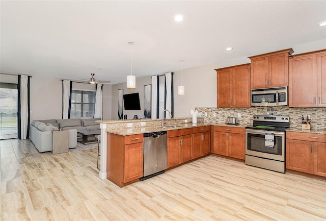 1403 Rolling Fairway Dr, Davenport, FL 33896 - kitchen featuring appliances with stainless steel finishes, a peninsula, brown cabinets, tasteful backsplash, and recessed lighting
