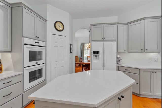 3372 Bellington Dr, Orlando, FL 32835 - kitchen featuring white appliances, gray cabinets, light countertops, arched walkways, and light wood-style flooring