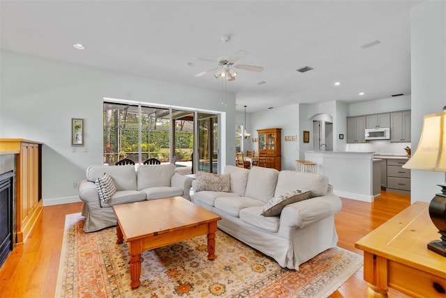3372 Bellington Dr, Orlando, FL 32835 - living room featuring light wood-type flooring, ceiling fan, recessed lighting, a glass covered fireplace, and baseboards