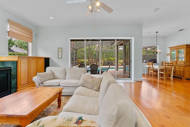 3372 Bellington Dr, Orlando, FL 32835 - living area featuring ceiling fan, light wood finished floors, a fireplace, recessed lighting, and a chandelier