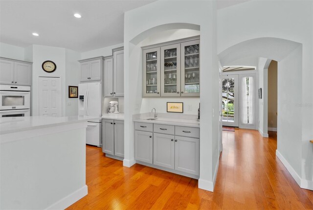 3372 Bellington Dr, Orlando, FL 32835 - kitchen featuring gray cabinets, a sink, arched walkways, light wood finished floors, and light countertops