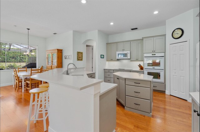 3372 Bellington Dr, Orlando, FL 32835 - kitchen featuring white appliances, a large island, gray cabinetry, light wood finished floors, and recessed lighting