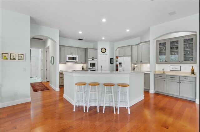 3372 Bellington Dr, Orlando, FL 32835 - kitchen with gray cabinets, white appliances, arched walkways, a breakfast bar area, and light wood-style flooring